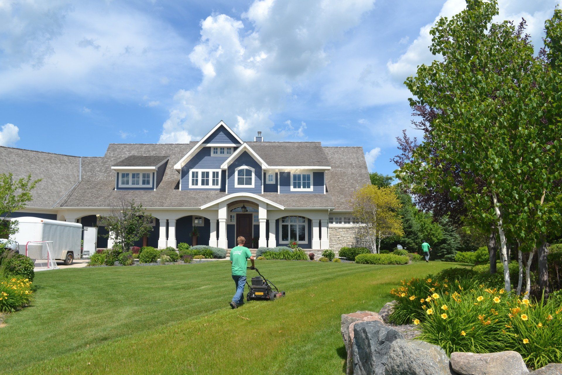 a man is mowing the grass in front of a large house