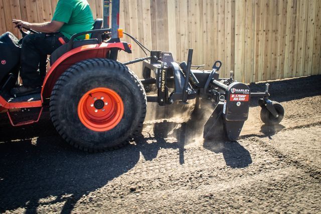 a man is driving a tractor with a plow attached to it .