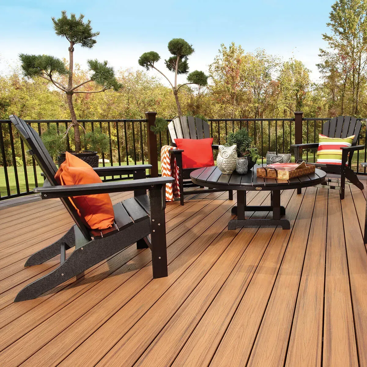 Outdoor deck with black Adirondack chairs and a round table.