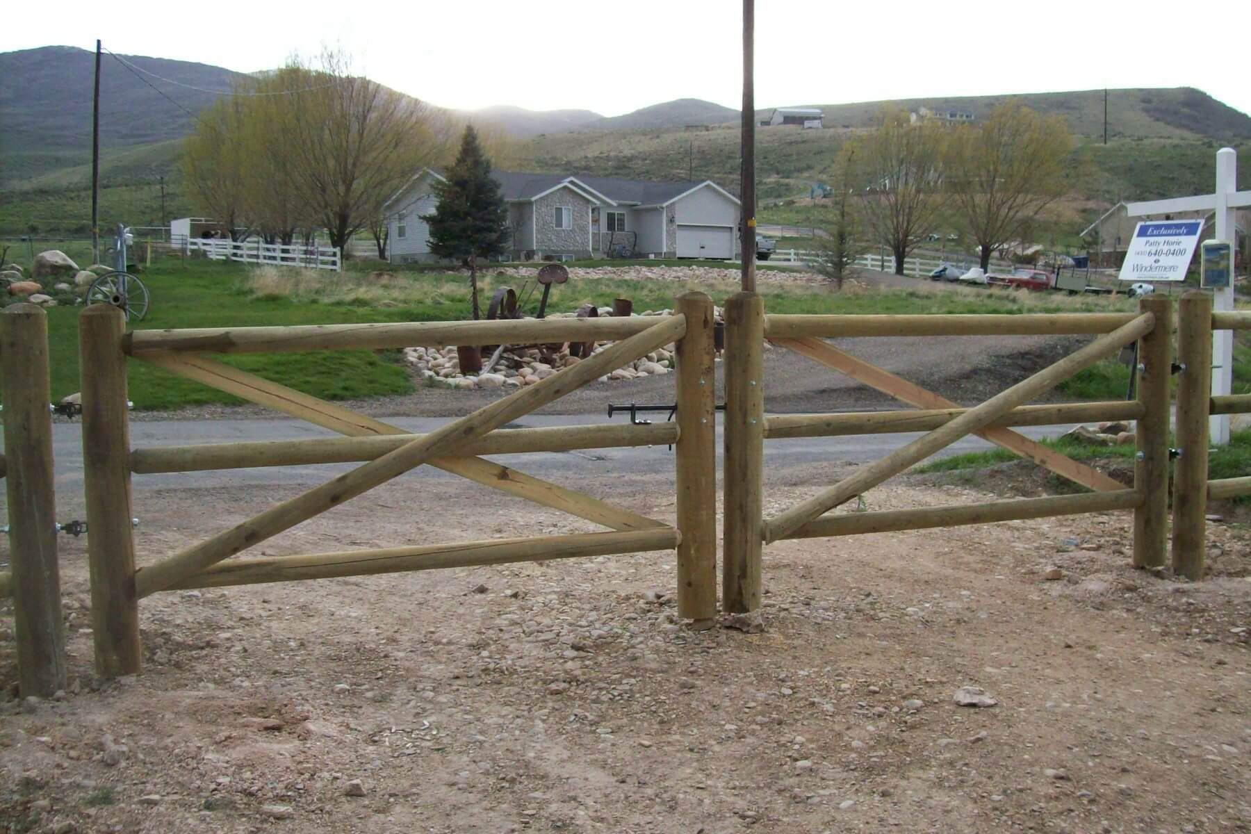 Wooden gate in front of a house, set in a rural, mountainous environment.