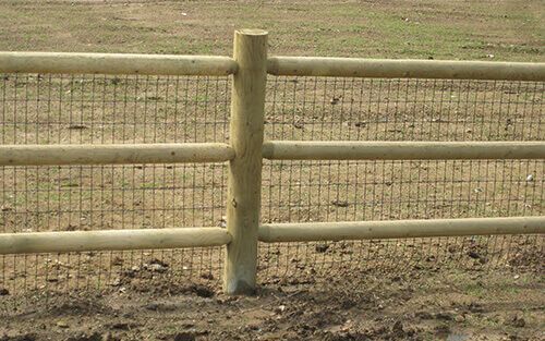 Wooden fence with wire mesh backing on brown earth.