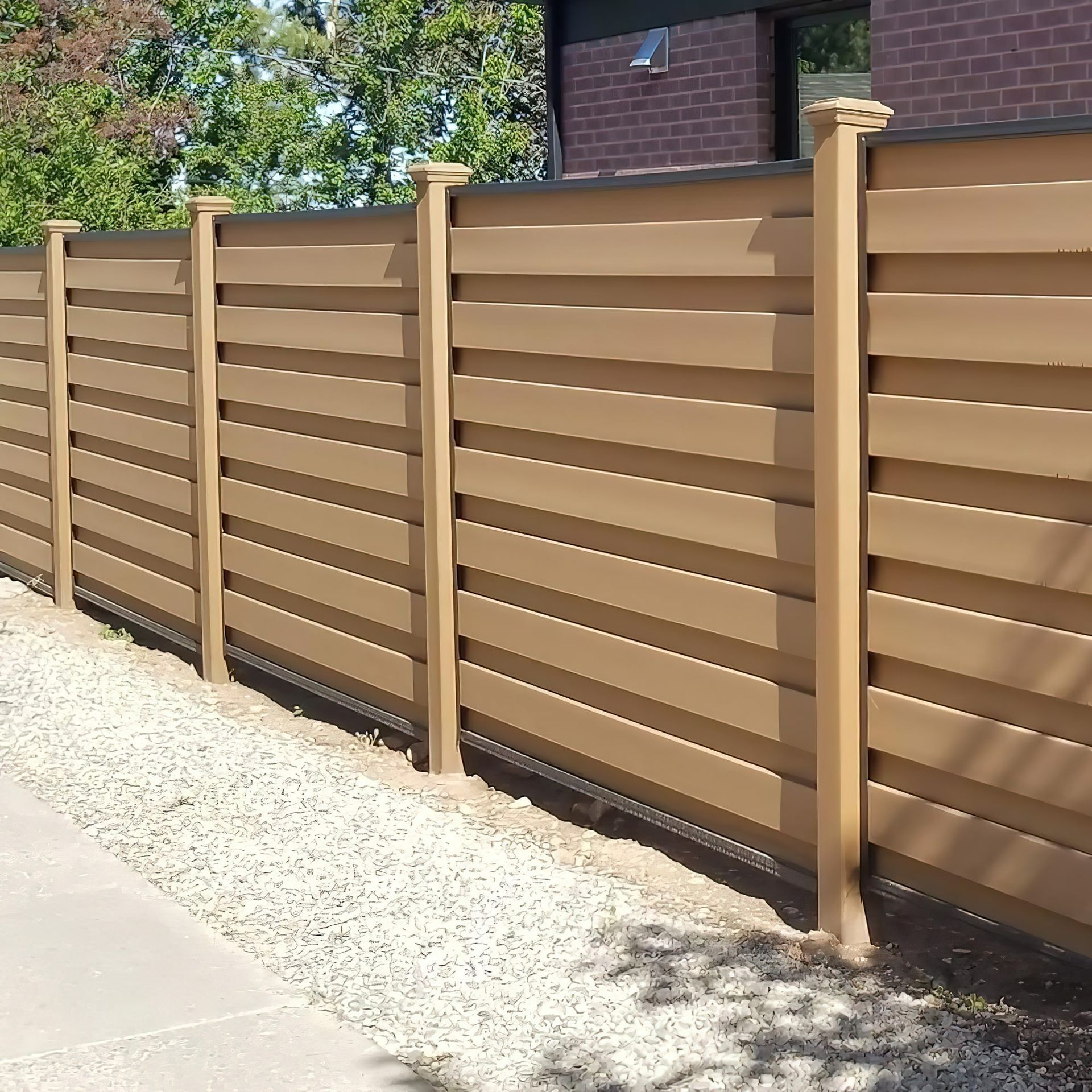 Brown horizontal slat fence with beige posts alongside a gravel path.