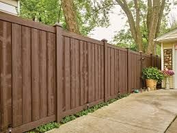 Brown wooden fence in a yard with a concrete path and potted plant.