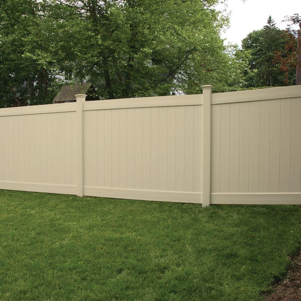 Beige vinyl fence enclosing green lawn, trees in background.