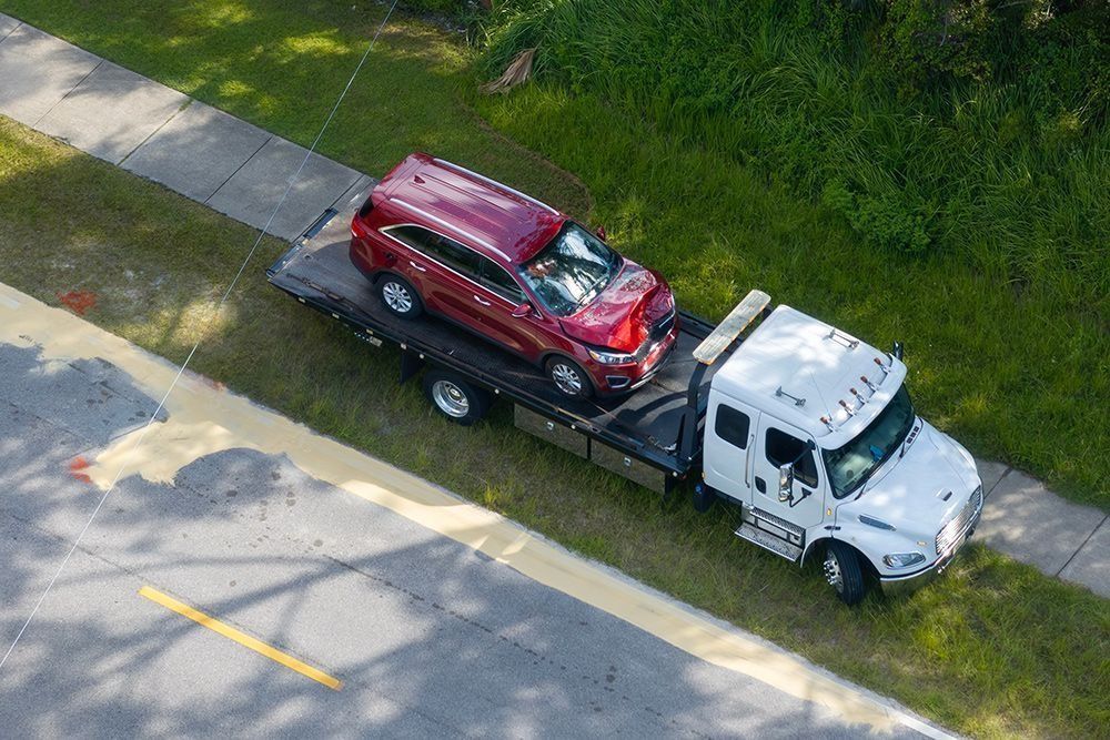 An aerial view of a tow truck carrying a red suv.
