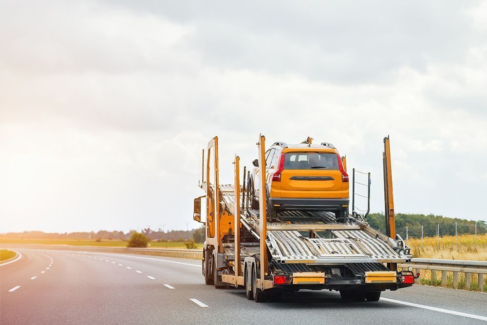 A tow truck is carrying a car on a highway.