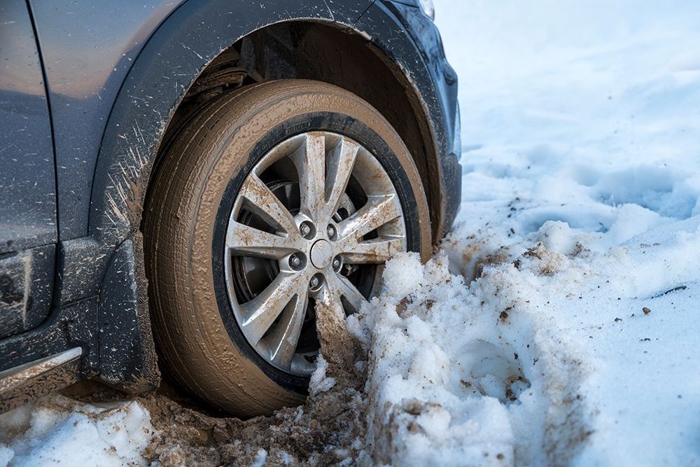 A car wheel is stuck in the snow.