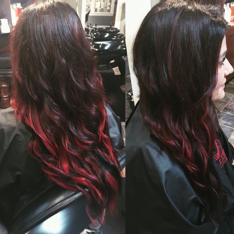 Woman with long, wavy dark hair with bright red tips, in a salon chair.
