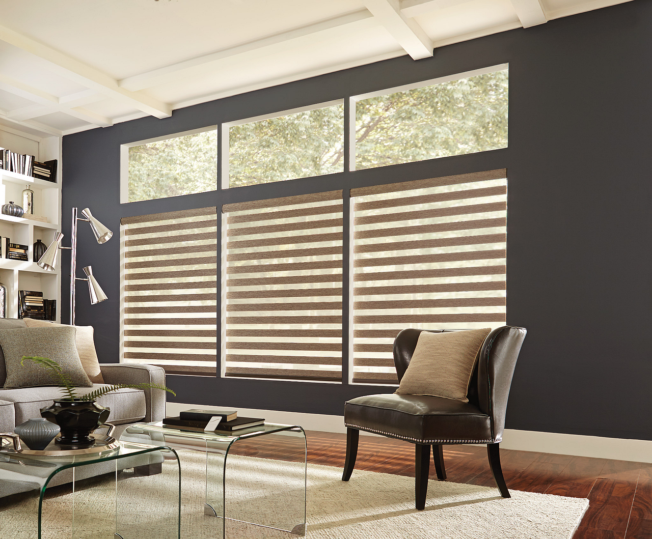 Modern living room with gray walls, large striped blinds, glass coffee table, and two chairs