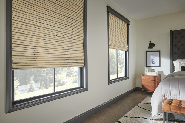 Bedroom with two windows, woven shades, gray walls, and a bed beside a small wooden dresser.