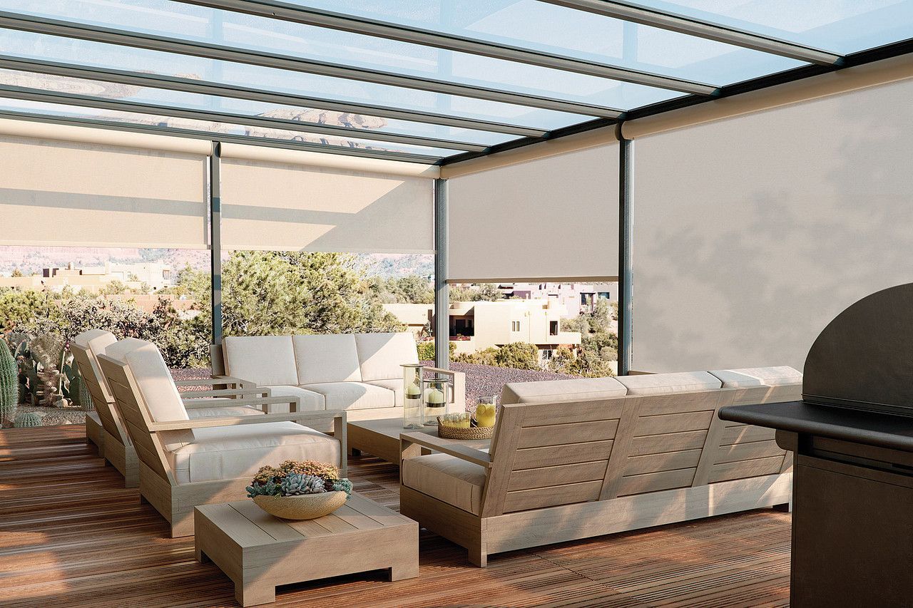 Modern outdoor patio with white cushioned seating, wooden deck, and a pergola roof overlooking a bright view.