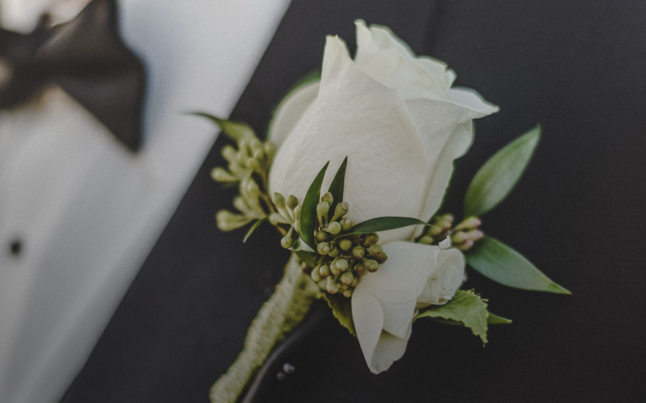 White rose boutonniere on a black tuxedo.