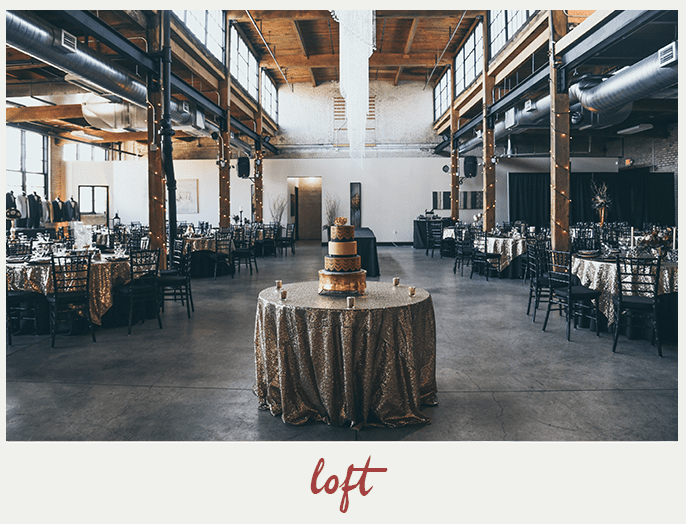 Wedding reception in a loft: tables set with gold linens, cake centerpiece, industrial beams, concrete floor.