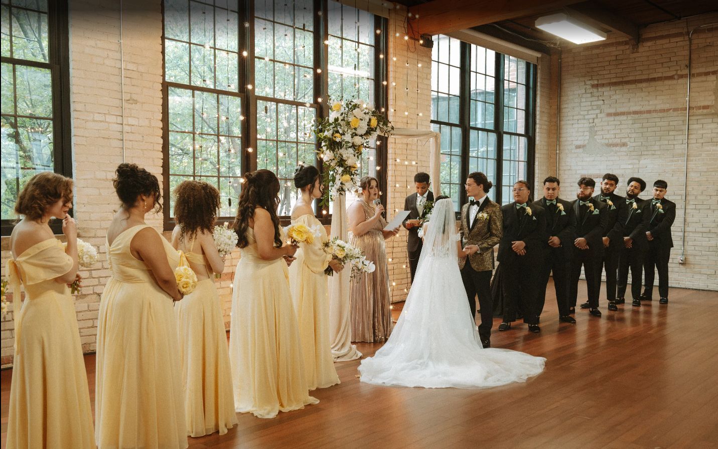 Wedding ceremony: bride and groom at altar, bridesmaids in gold dresses, groomsmen in black suits, indoor space.