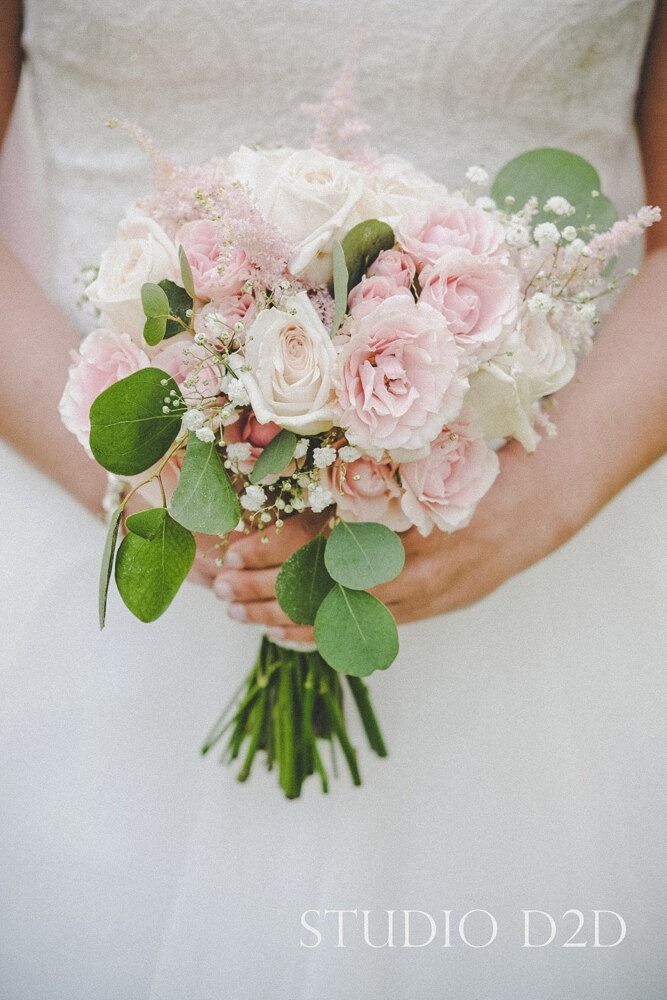 Bride holding a bouquet of pink and white roses, eucalyptus, and baby's breath.