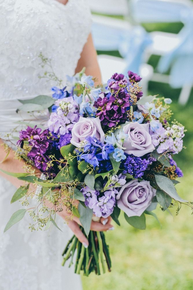 Bride holding a bouquet of purple and blue flowers.