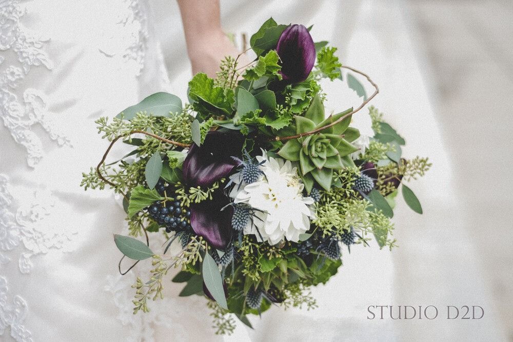 Bride holding a bouquet of dark purple and green flowers.