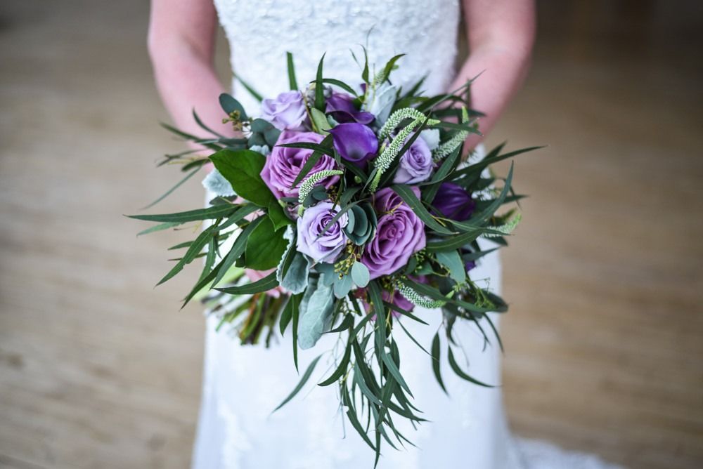 Woman holding purple and green flower bouquet.