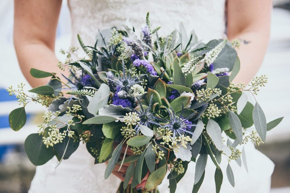 Bride holding a bouquet of purple and green flowers.