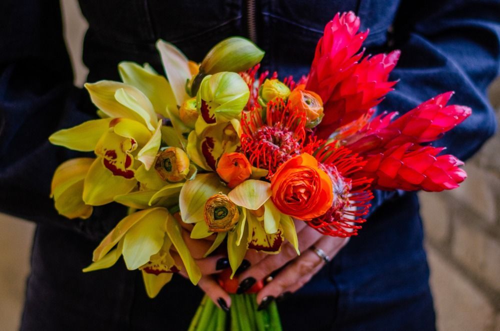 Person holding a bouquet of yellow and red flowers.