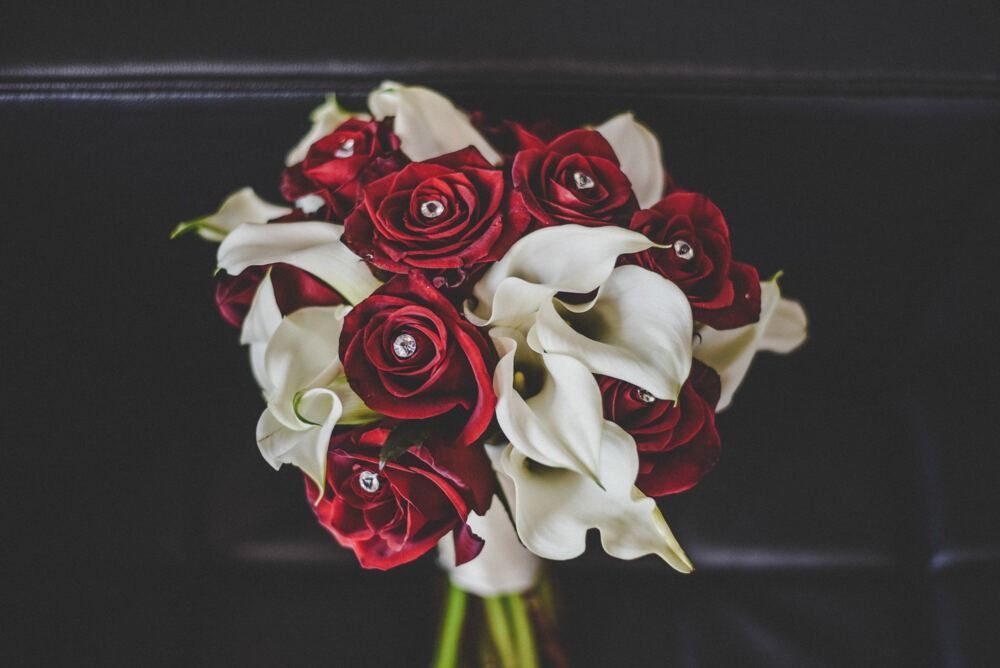 Bouquet of red roses and white calla lilies, some roses with rhinestones.