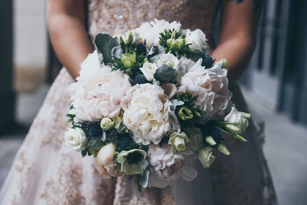 Bride holding a bouquet of white and blush flowers, with a pale peach dress.