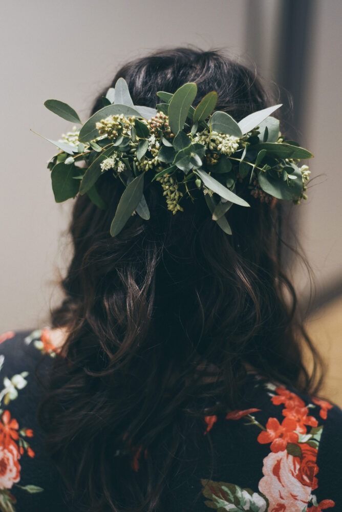 Woman wearing a floral crown in her hair; dark wavy hair, floral print robe.