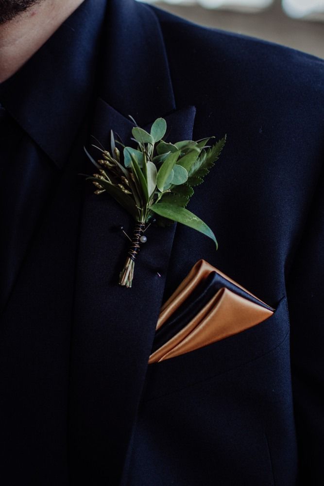 Man's navy suit with a floral boutonniere and a gold pocket square.