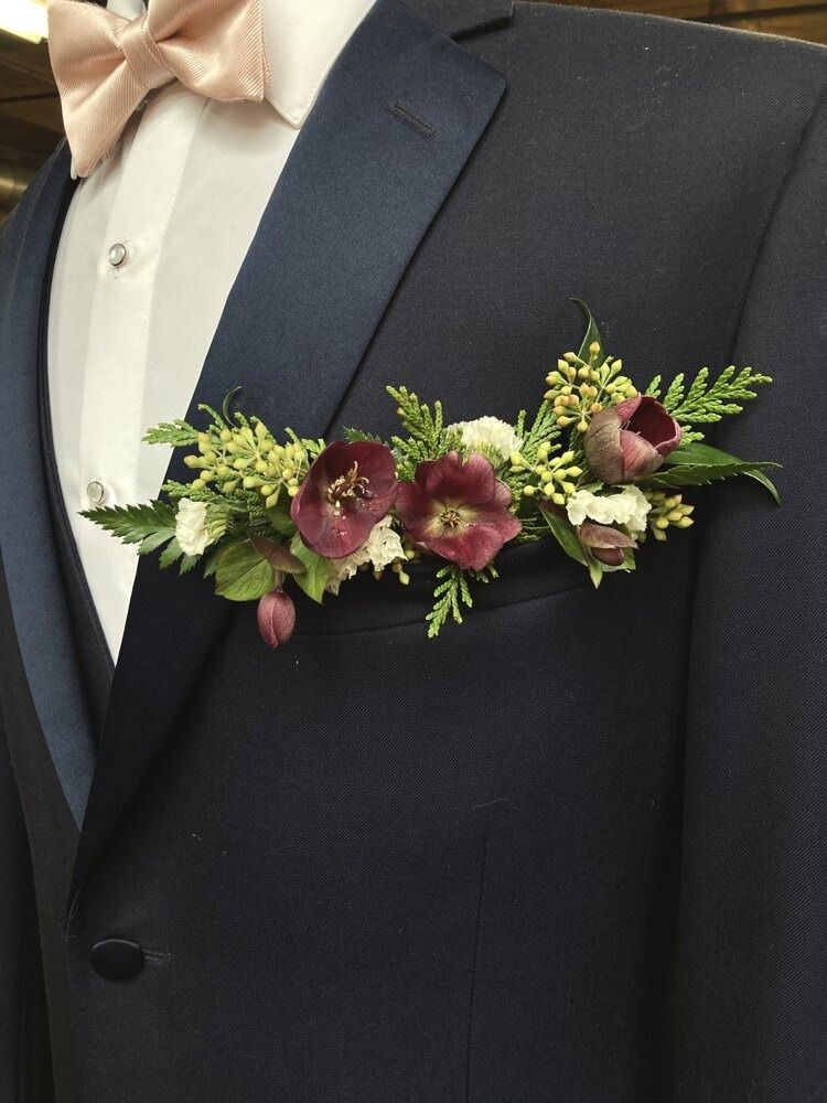 Dark blue suit with boutonniere of burgundy and white flowers, pale pink bow tie.