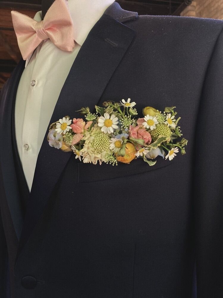 Navy suit with flower pocket square, pink bow tie.