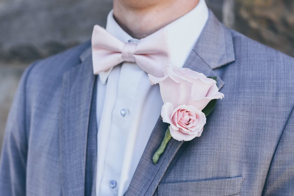 Man in gray suit with pink bow tie and rose boutonniere.
