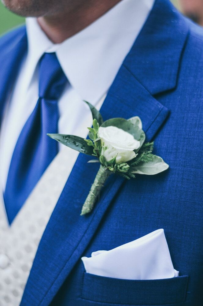 Groom in blue suit with white boutonniere and pocket square.