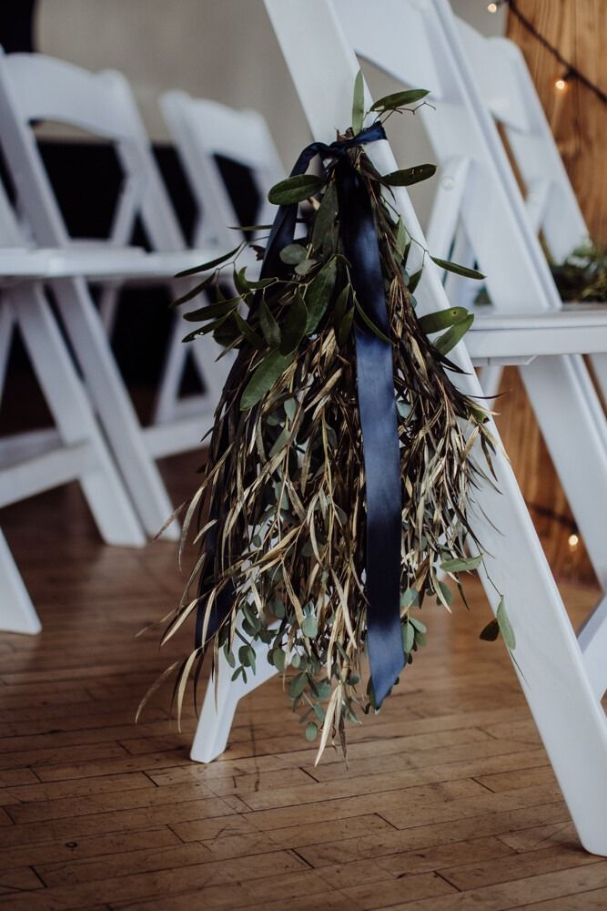 White chairs with navy ribbon and floral decorations.