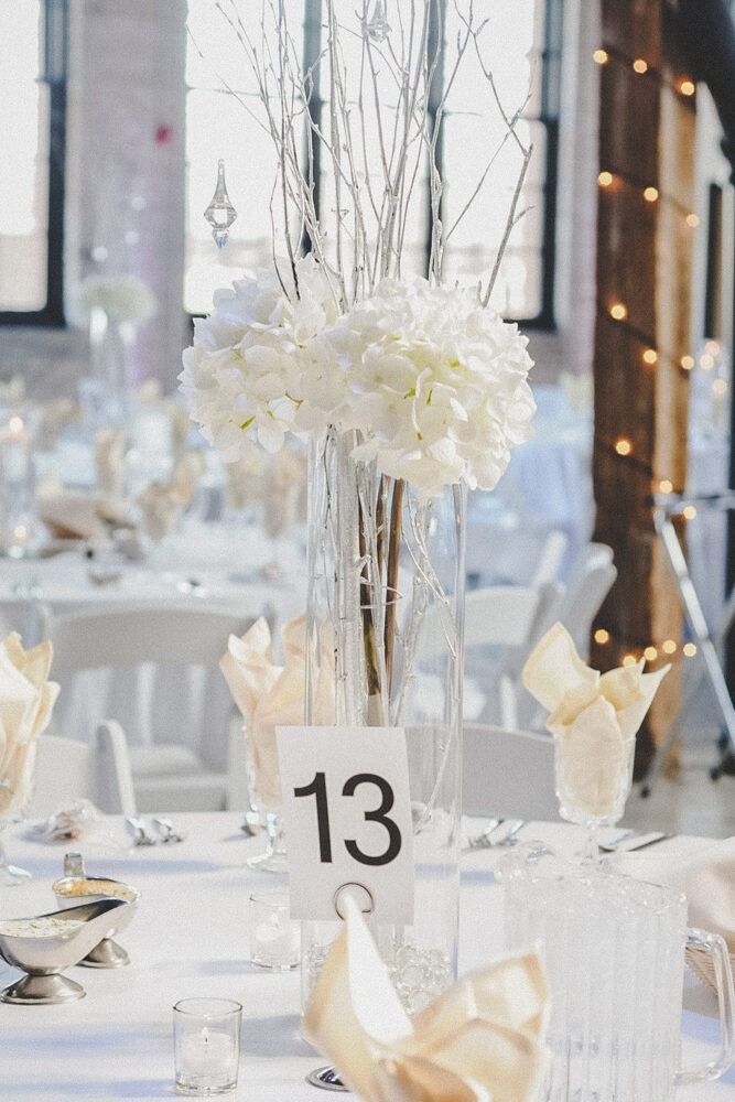 Elegant white wedding table setting with floral centerpiece and table number 13.