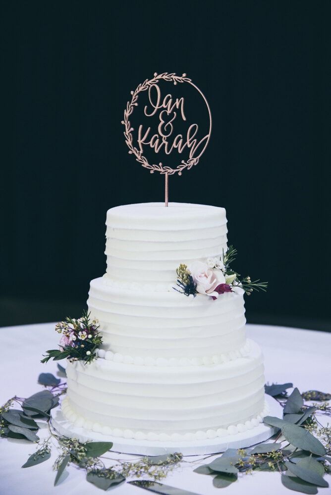 Three-tiered white wedding cake with floral accents and a circular 