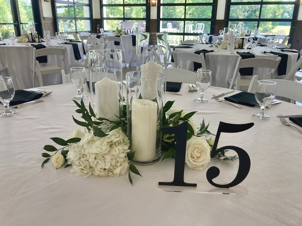 Table setting with centerpiece of candles, flowers, greenery, and table number 15.