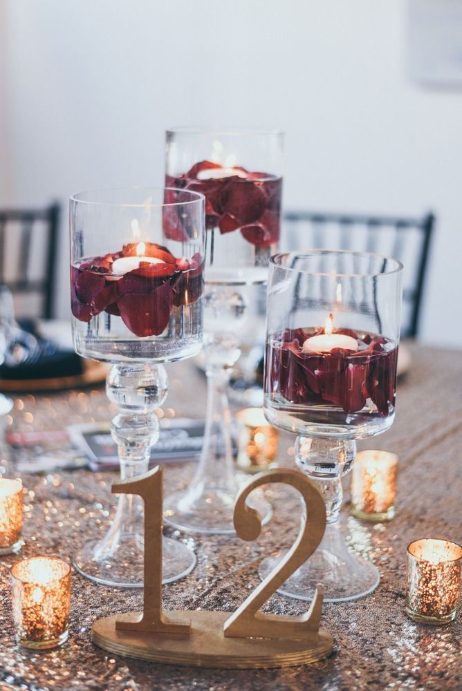 Elegant table centerpiece with floating candles and gold table number 12.
