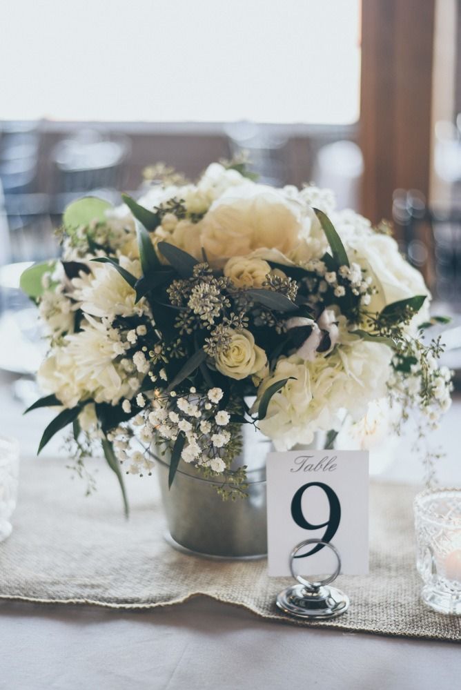 Centerpiece of white flowers, table number 9, on a rustic table setting.