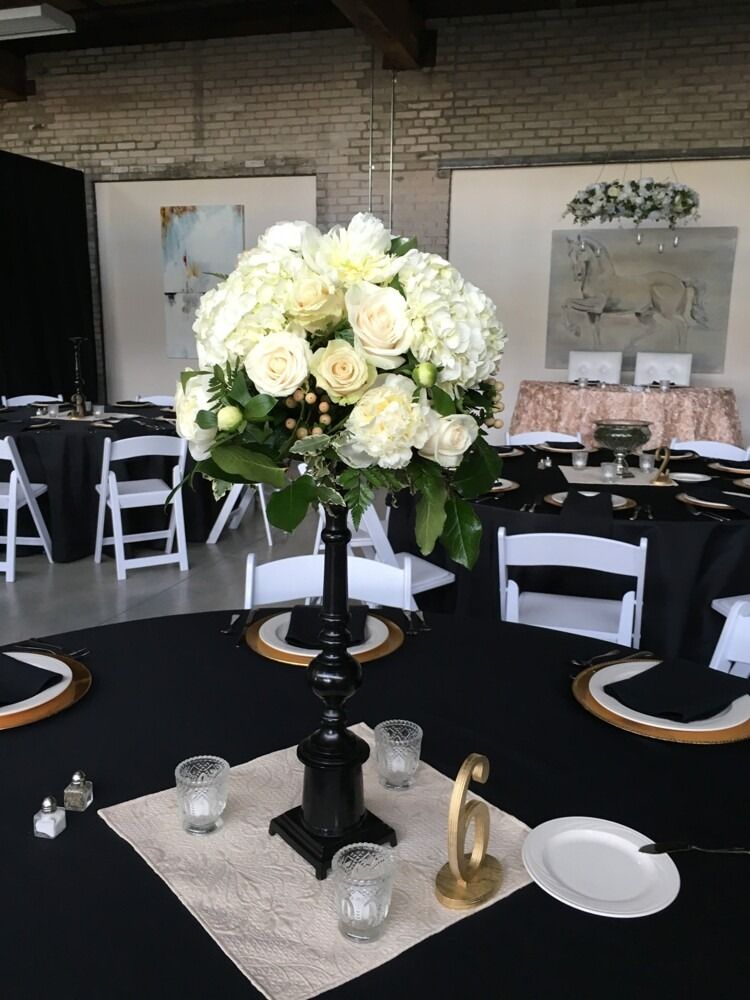 Elegant table setting with white floral centerpiece and black tablecloths.