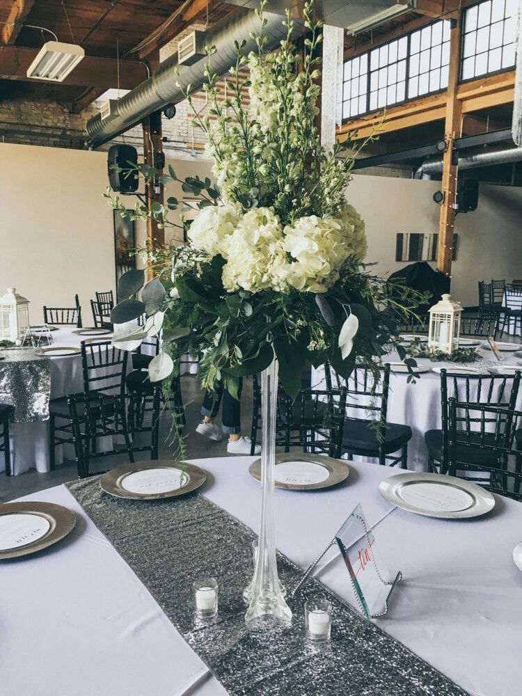 Wedding reception table setting with floral centerpiece and place settings.