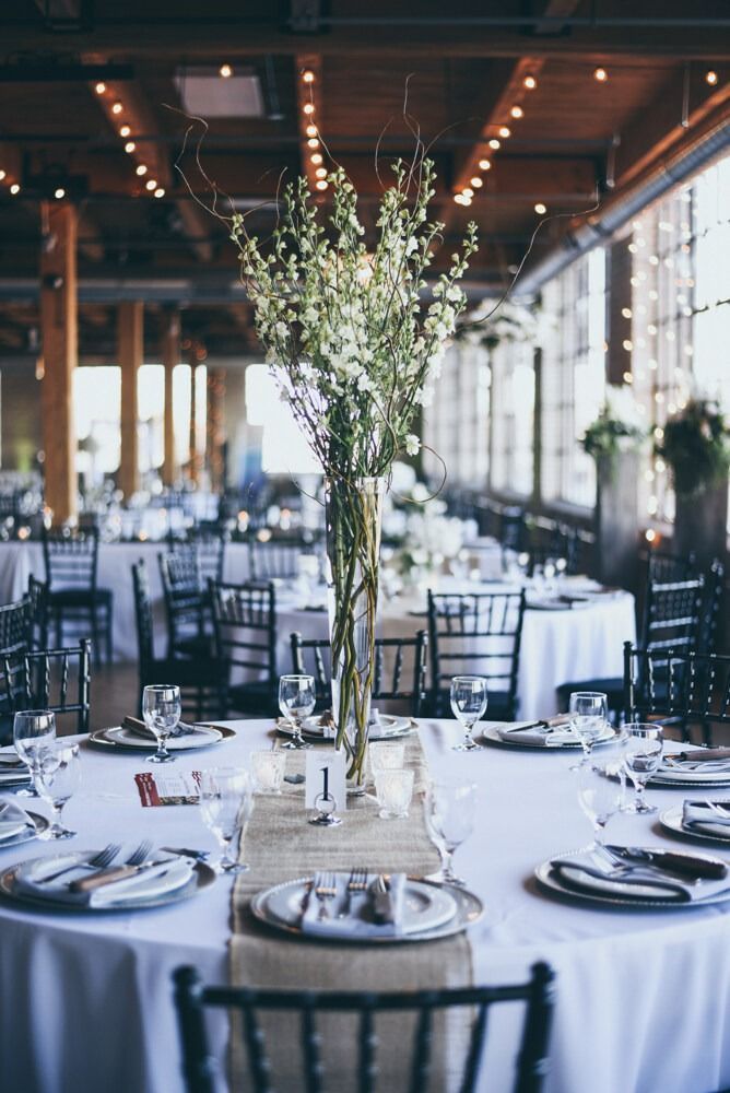 Wedding reception with round tables, floral centerpieces, and string lights.