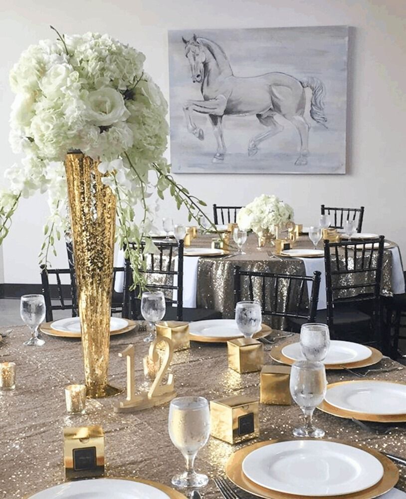 Elegant table setting with gold sequin tablecloth, white flowers, and horse painting.