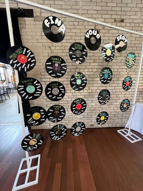 Wall of vinyl records with guest names, part of a seating chart display.