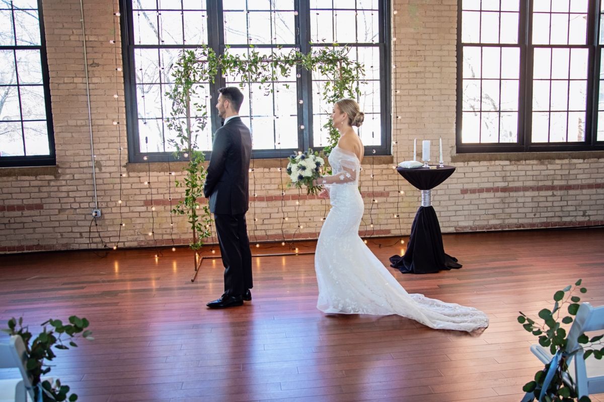Bride and groom at altar. Bride in white gown facing groom. Wedding ceremony indoors.