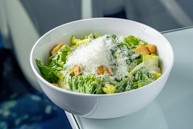 Caesar salad in a white bowl topped with grated cheese and croutons
