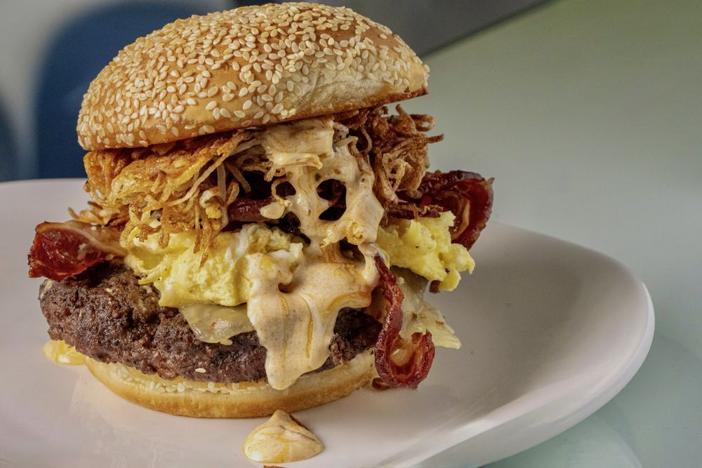 Loaded cheeseburger with bacon, melted cheese, and sauce on a white plate