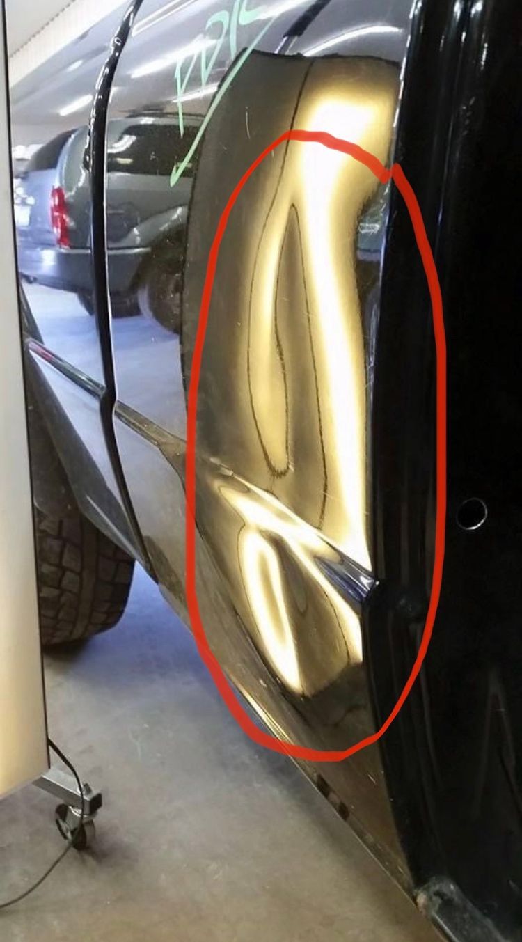 A close-up of a car with a dent circled in red 