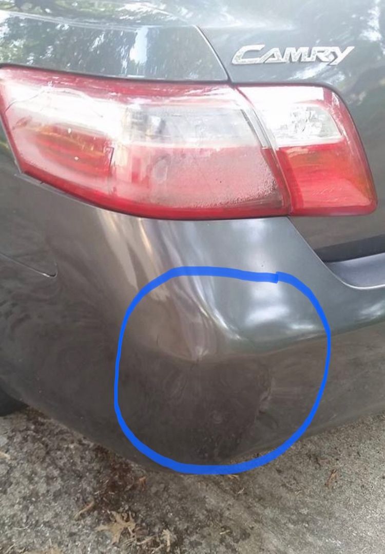 A close-up of a gray car with a fixed dent at the back circled in blue