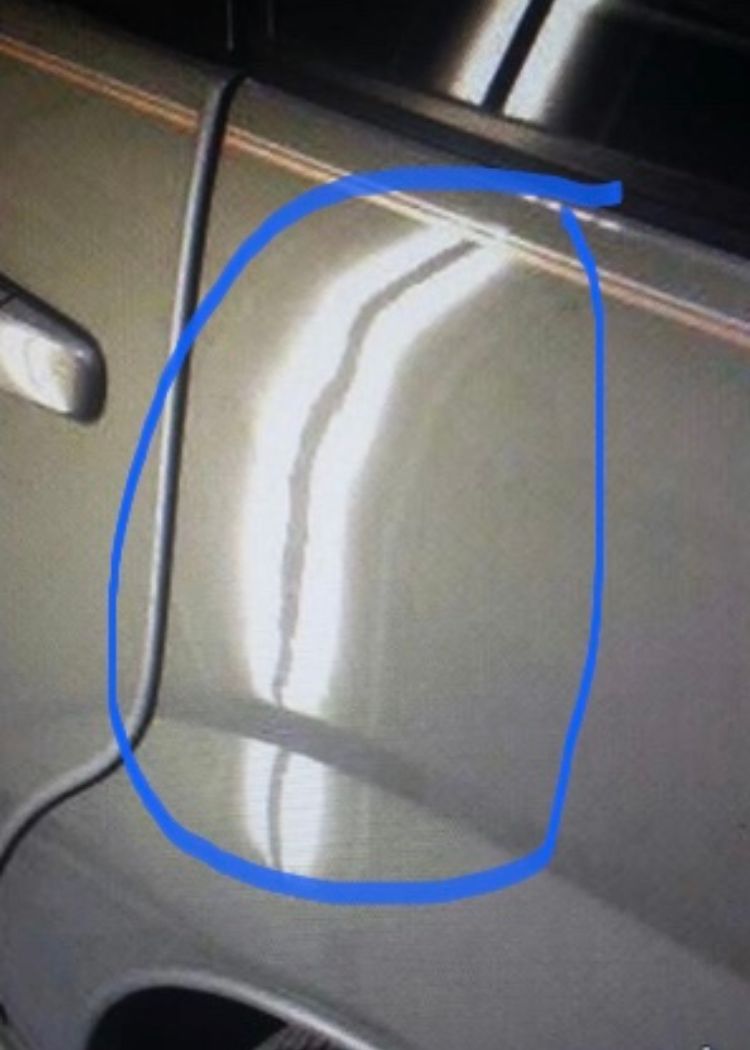 A close-up of a car with a fixed dent circled in blue
