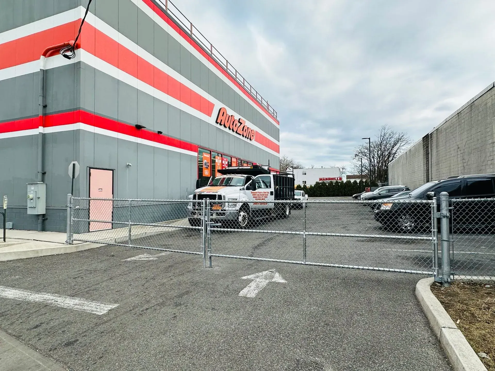 Truck at a storage facility gate; building has red and orange stripes.